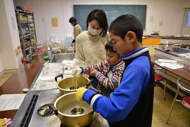 親子が鍋で廃油処理剤を湯煎している写真