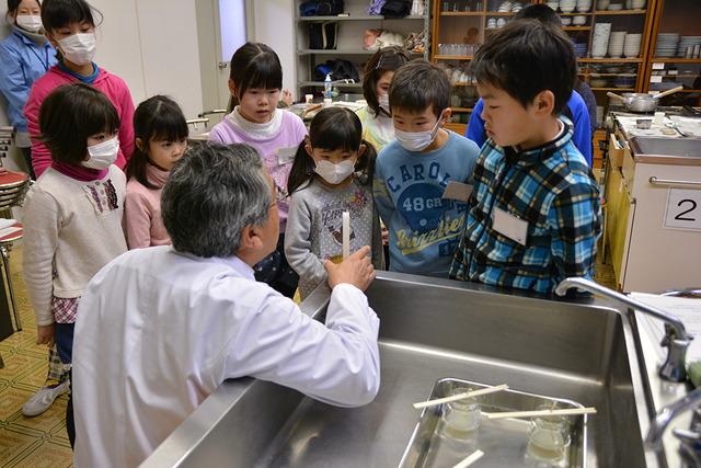 子どもたちがロウソクを持った館長の話を聞いている写真