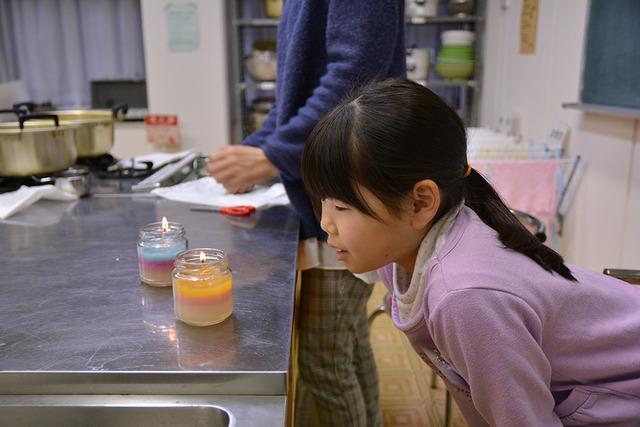 女の子が火が灯ったキャンドルを眺めている写真