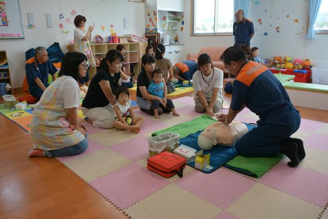 子連れの人や保育士が胸部マッサージの訓練を受けている写真