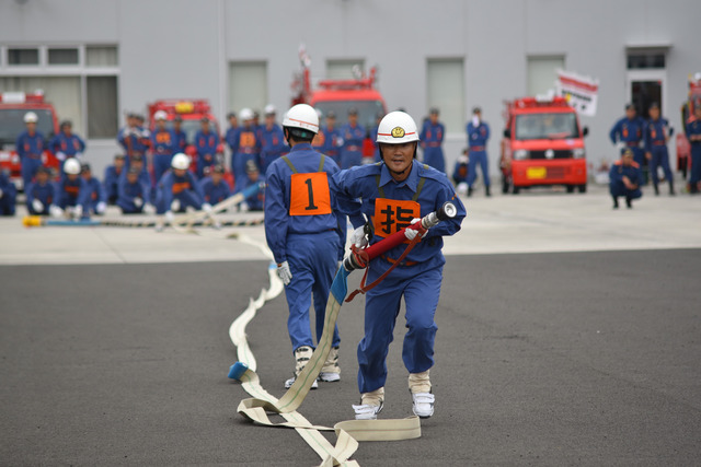 (写真)小型ポンプ操法にてホースを伸ばしながら走る団員
