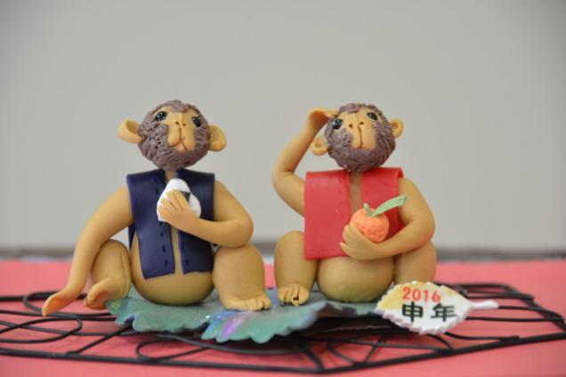 紙粘土で作ったおにぎりを持っている青い服を着た申と、ミカンを持っている赤い服を着た申の写真