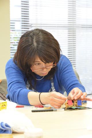 1人の女性が真剣な表情で申を製作している写真