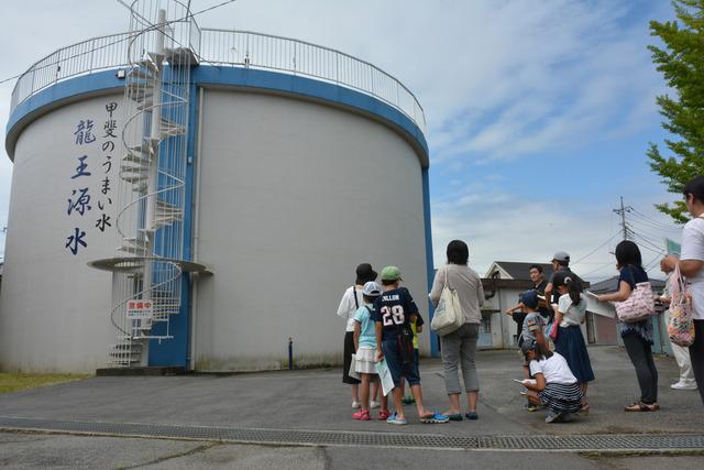 大きな円柱型の排水池の前で説明を聞く親子の写真