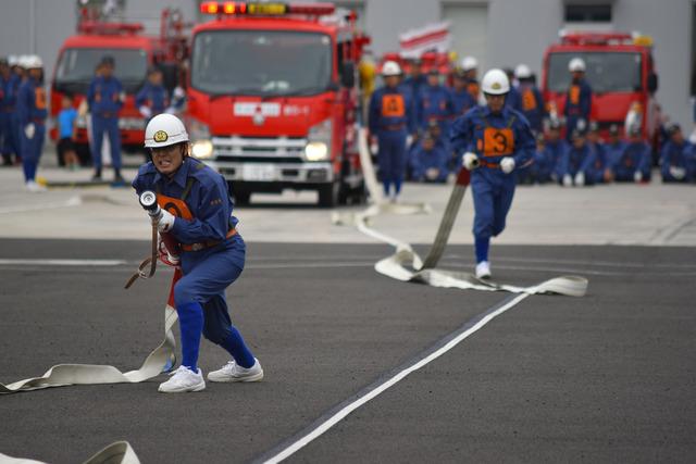 (写真)ポンプ車操法にてホースを伸ばしながら走る団員