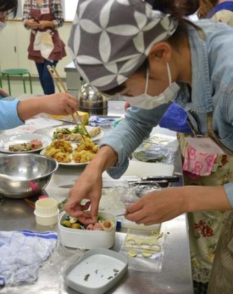 1人の女性がお弁当箱におかずを詰めている写真
