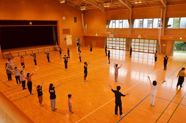 体育館で広がって円になり踊っている講習会の写真