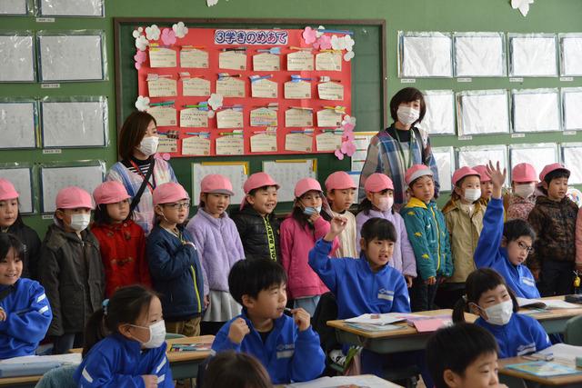 小学校の教室の中に入り、授業を見学する園児の写真