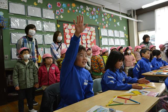 小学校の教室の中に入り、授業を見学する園児の写真