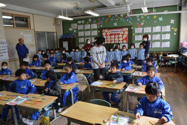 小学校の教室の中に入り、授業を見学する園児の写真