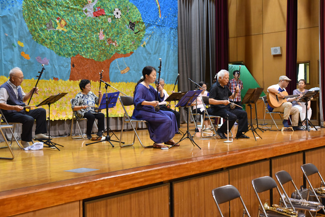 体育館の舞台で地域のクラブの皆さんが二胡の演奏をしている写真