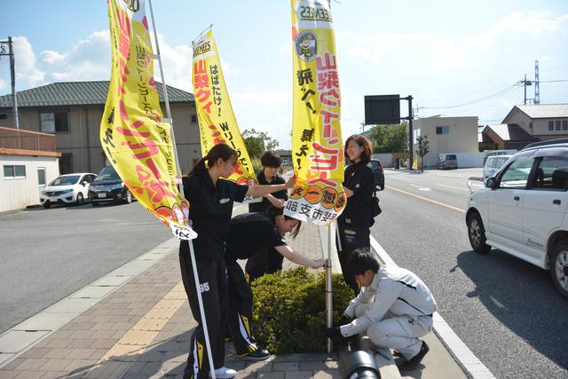 のぼり旗を歩道に取り付けている様子の写真