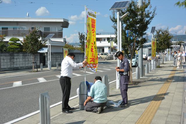 のぼり旗を歩道に取り付けている様子の写真