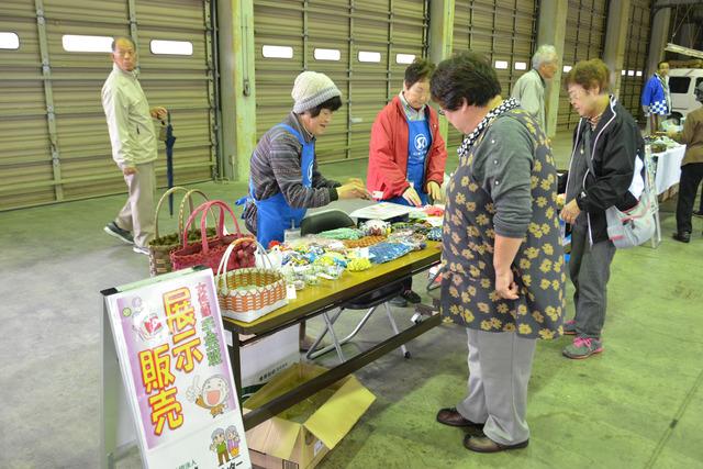 手芸展示販売を行う女性と作品を見ている女性たちの写真