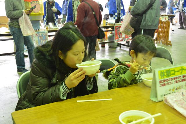休憩コーナーで豚汁を味わう親子連れの写真