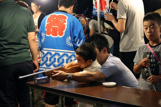 祭りで射的を楽しむ親子の写真