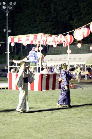 櫓の周りで盆踊りをする人の写真