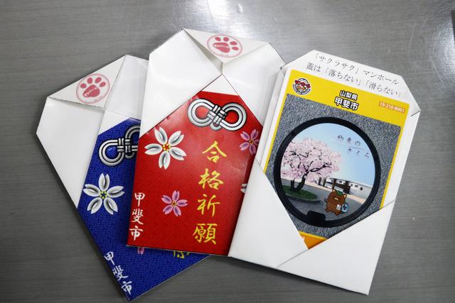 「合格祈願」の文字が印刷された用紙とマンホールカードの写真