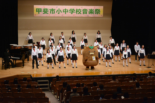首に赤いリボンを付けた敷島小学校合唱部の写真