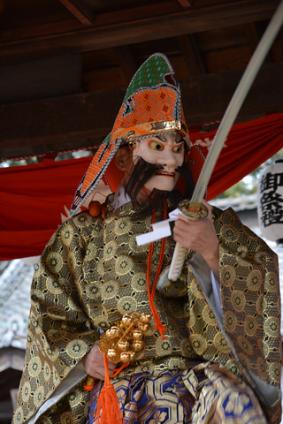 衣装を着て面をつけた神楽の写真