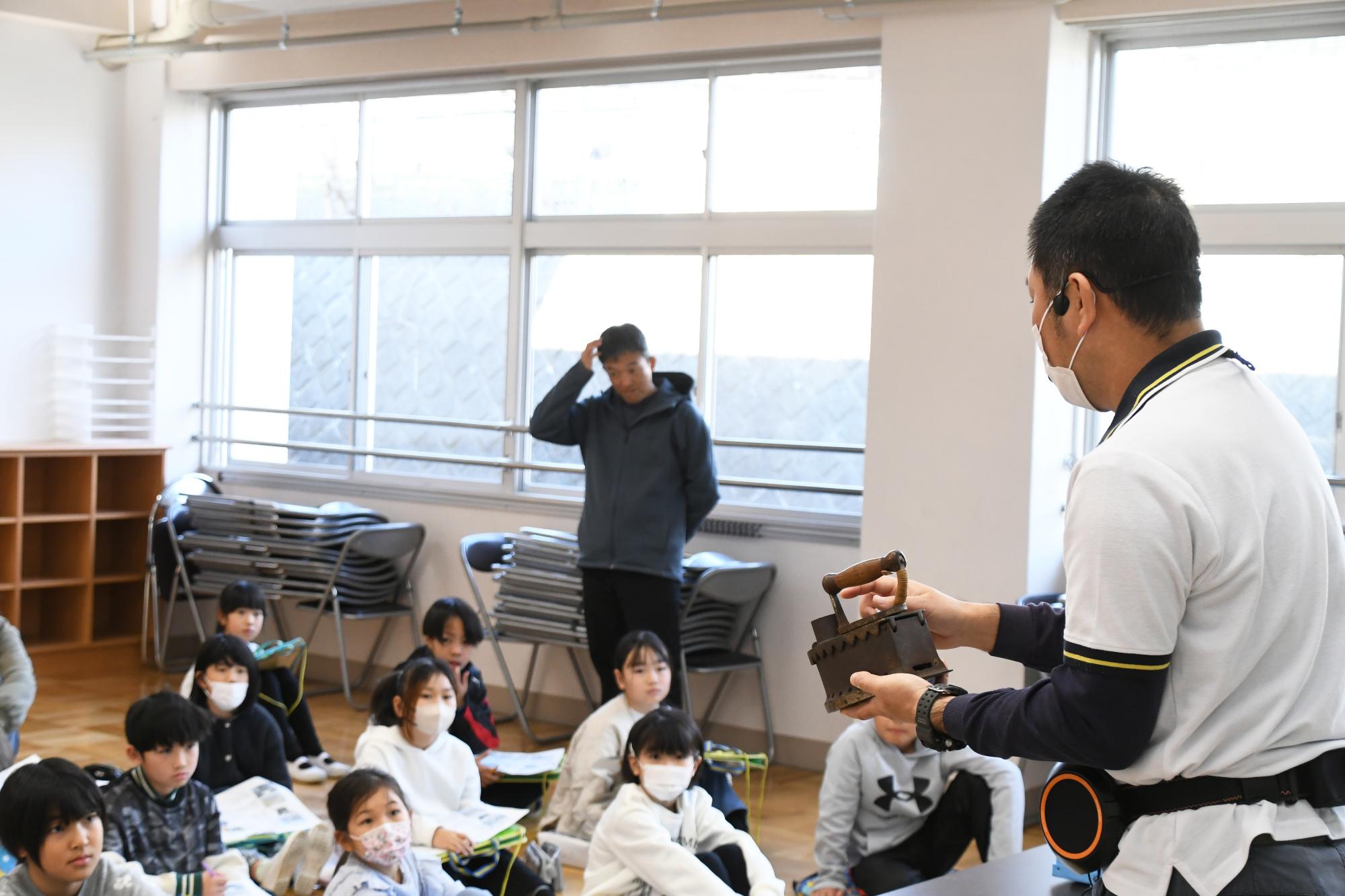 炭火アイロンを手に授業をする講師の写真