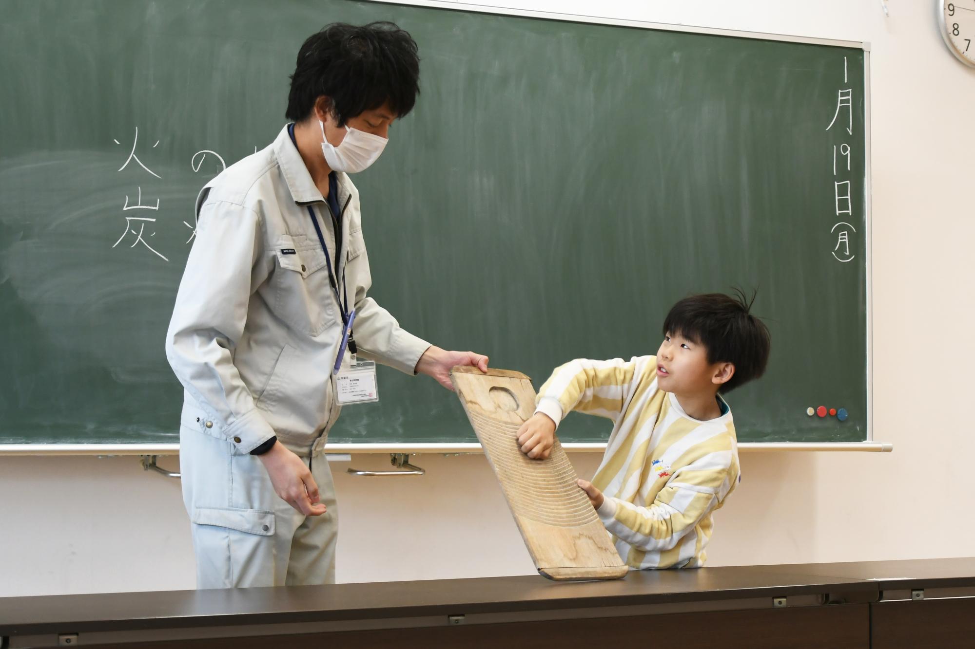 洗濯板の使い方を実演する講師と児童の写真
