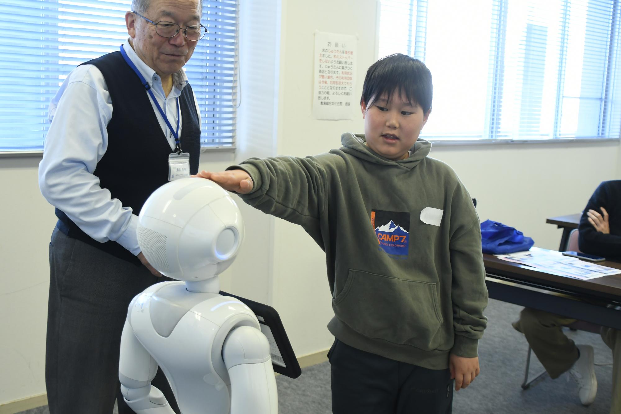 ロボットのペッパー君の頭をなで指示を送っている様子