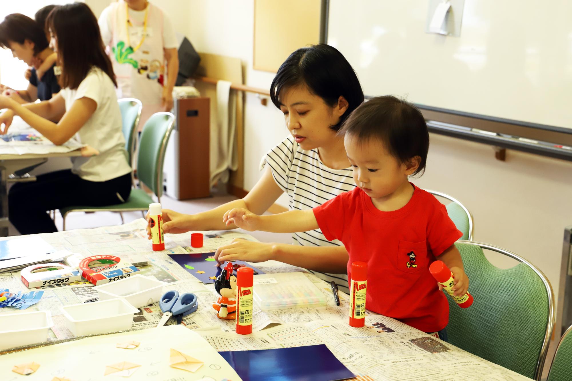 飾りを子どもがのりつけしています