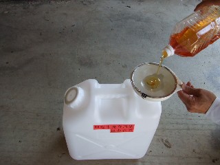 ペットボトルに入っている廃食用油をポリ容器に移している写真