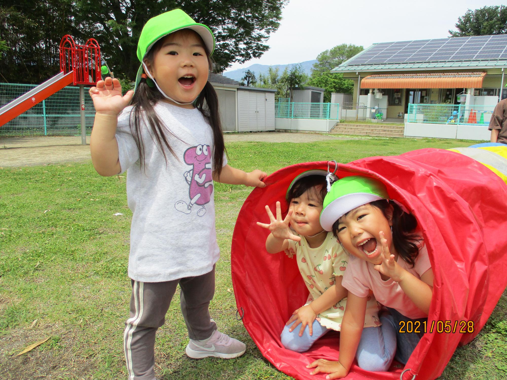 トンネルから顔を出して楽しむすみれ組の子ども達。