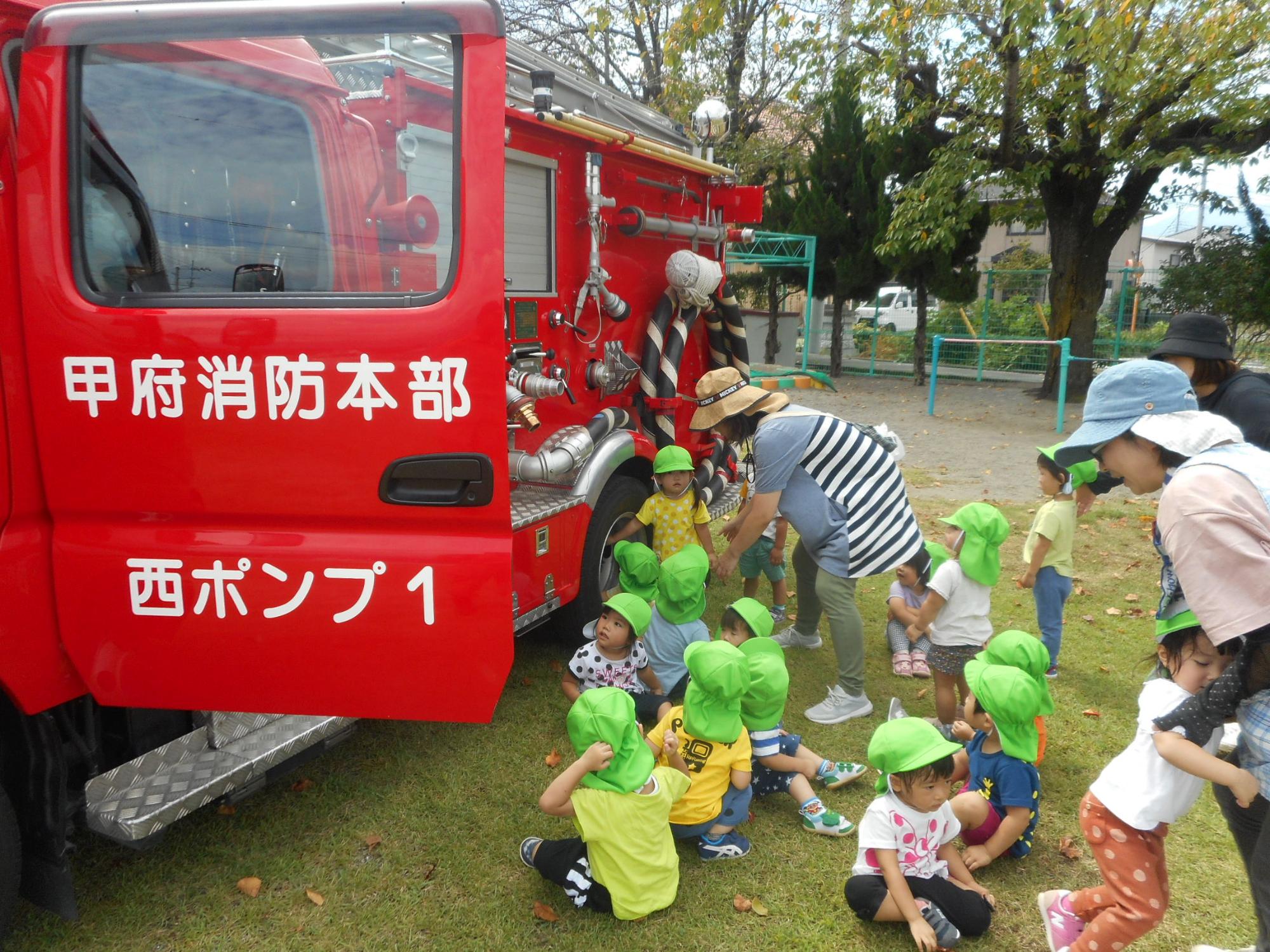 避難総合訓練で来園した消防車を見学するつぼみ1組の様子です。