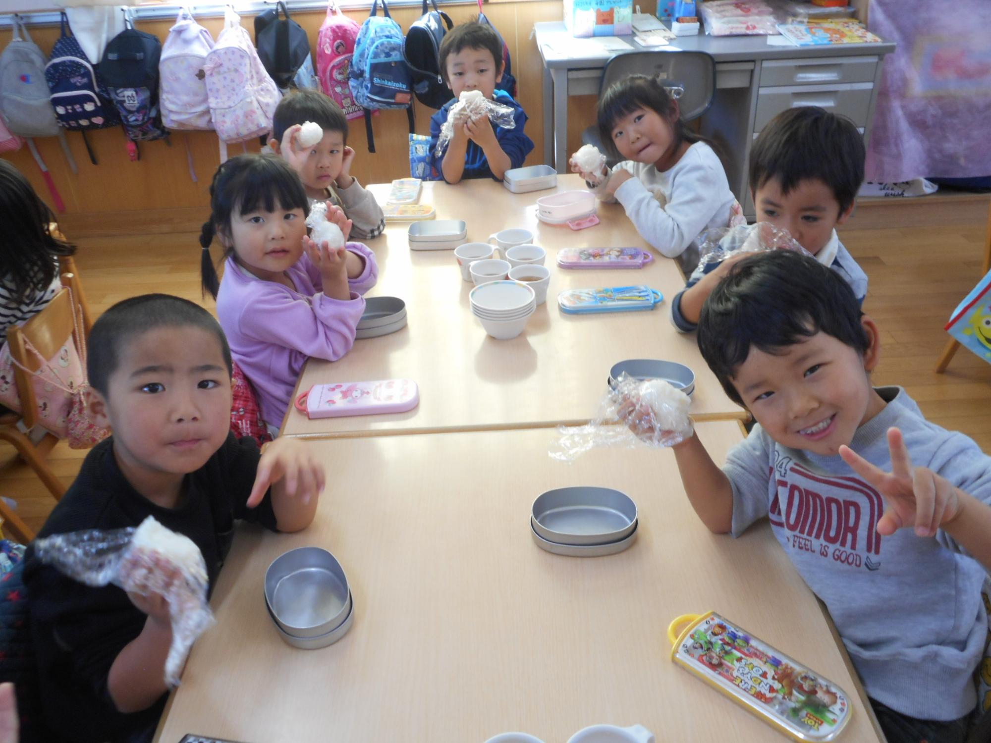 新米で作ったおにぎりを自分たちで握って食べる様子です。