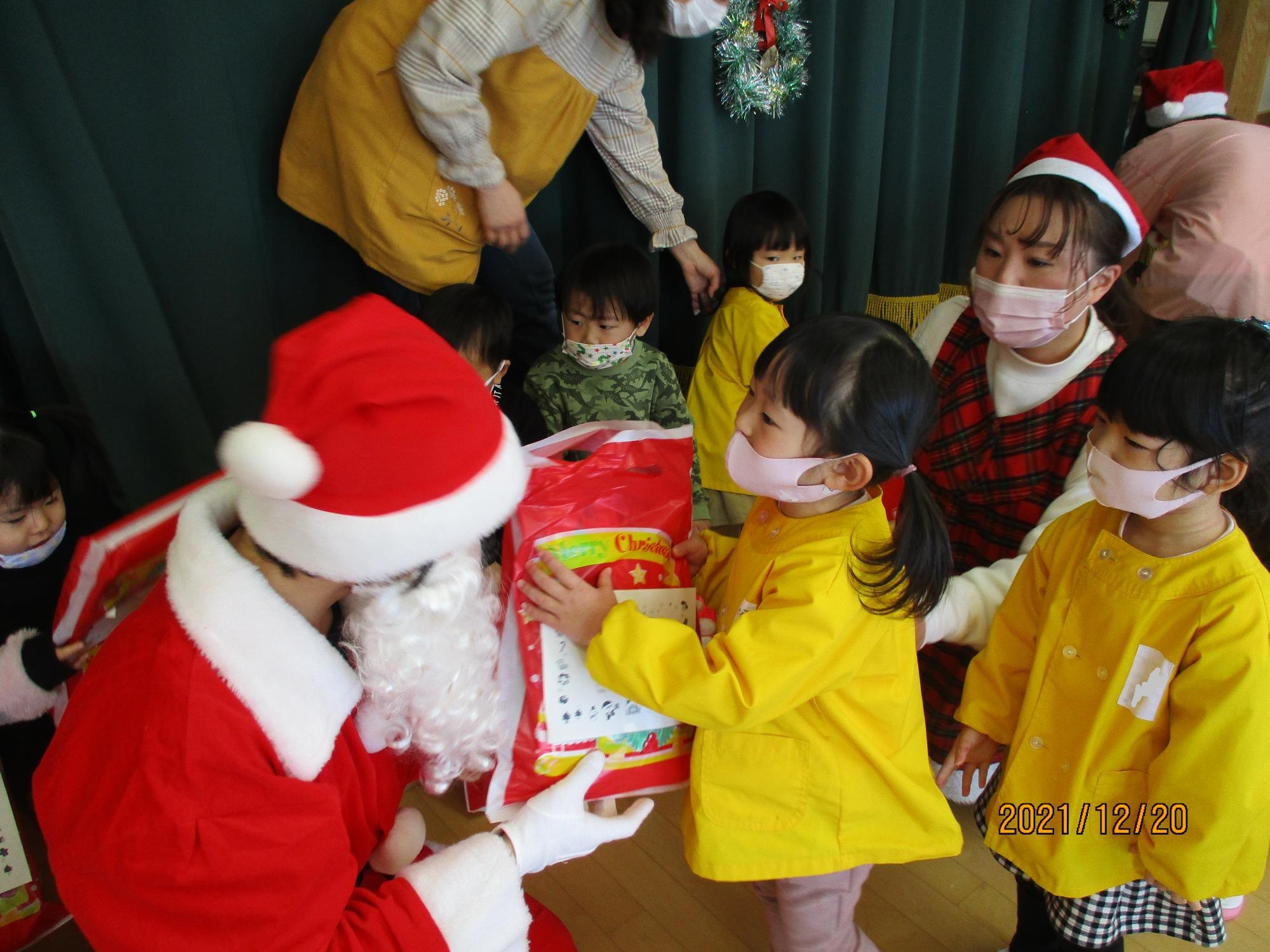 サンタさんからプレゼントをもらうすみれ組の子ども達です。