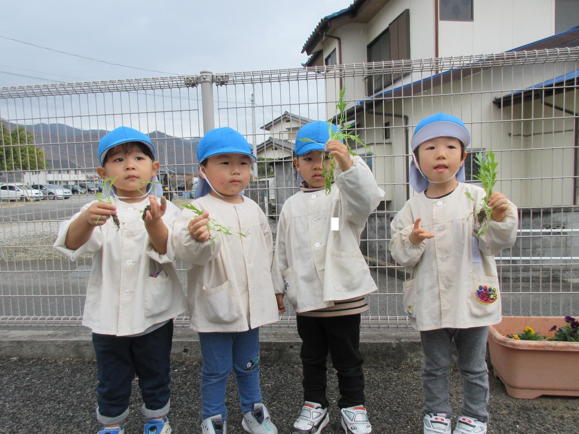 収穫した水菜と一緒に写真を撮るあお組