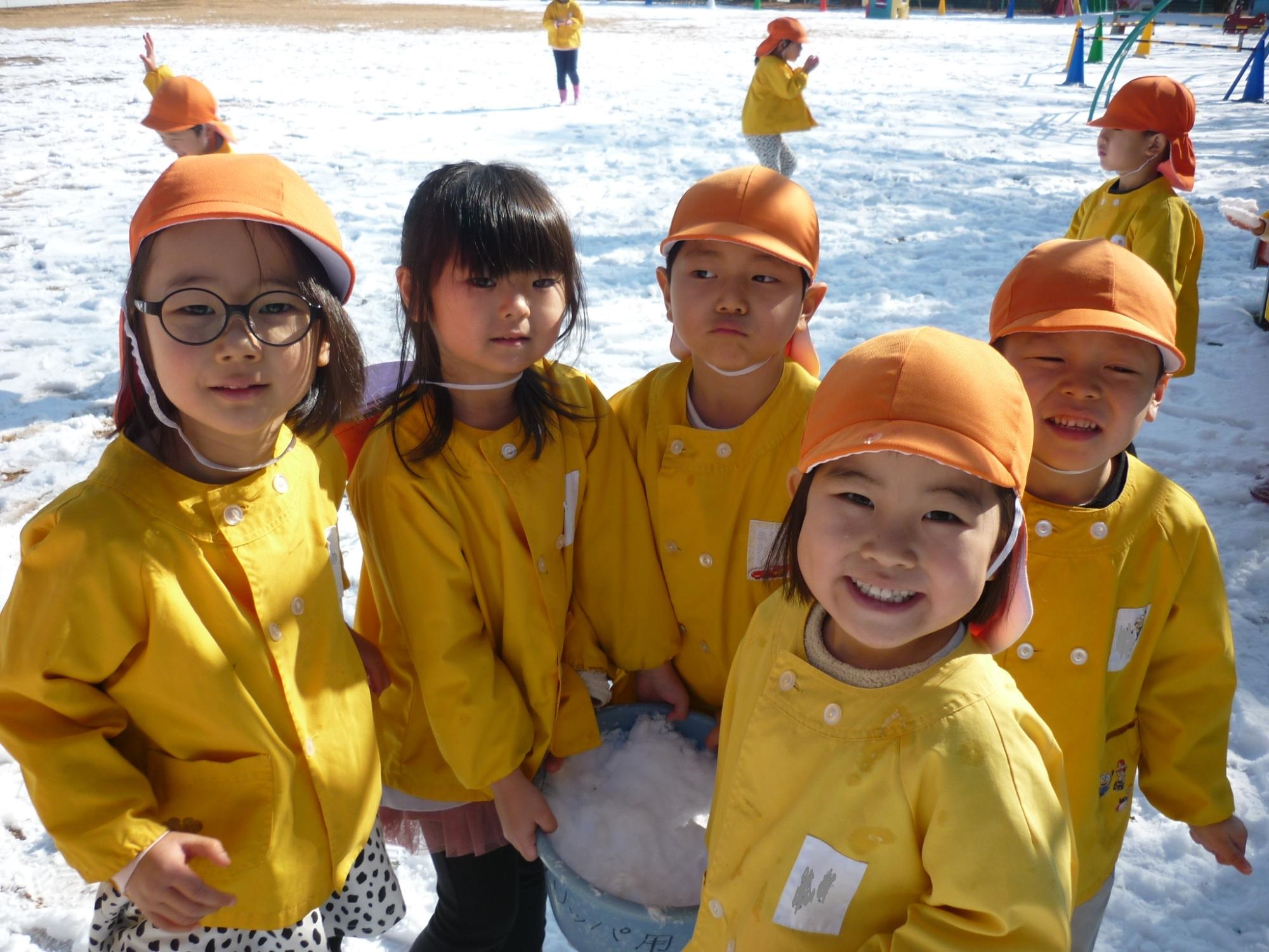 雪をバケツに集めて遊んでいる様子。