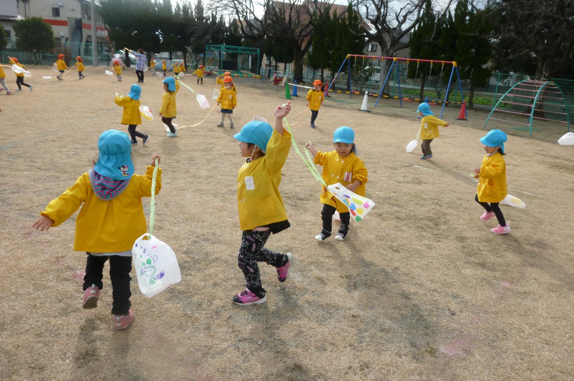 お正月遊び（凧あげ）を楽しみ園庭を走り回っているつぼみ2組の様子です。