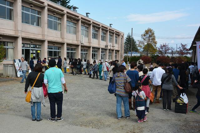 校舎の前に沢山の人が集まり行列を作っている写真