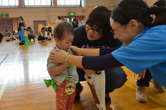 小さな男の子が先生からメダルをかけてもらっている写真