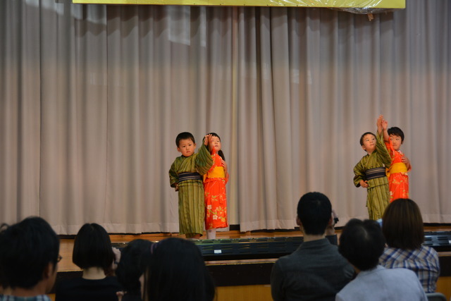 舞台で着物を着て踊る小さな子どもたちの写真