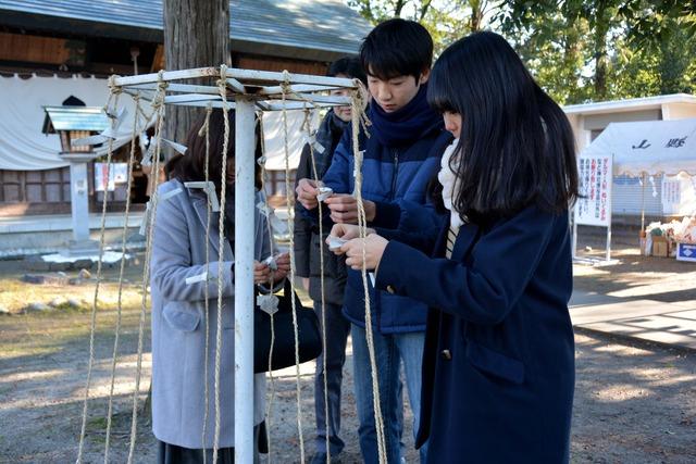 おみくじを結ぶ人々の写真