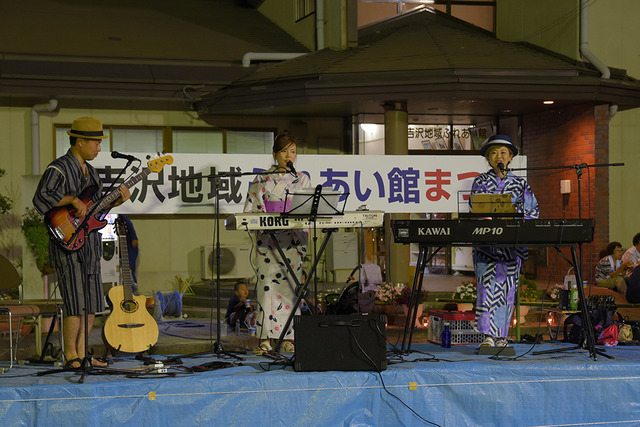 ステージ上で浴衣を着た人が歌を歌ったり、キーボードやギターを弾いている写真
