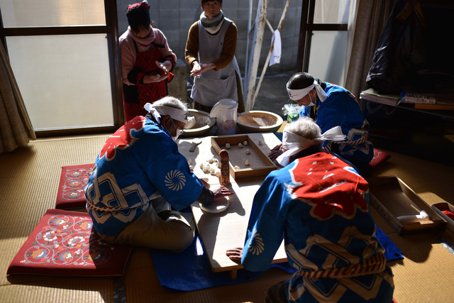 青い法被を着た人々が米の粉を練った生地で男女の性器を形作っている写真
