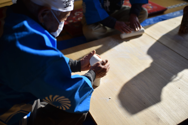青い法被を着た人が米の粉を練った生地で男女の性器を形作っている写真