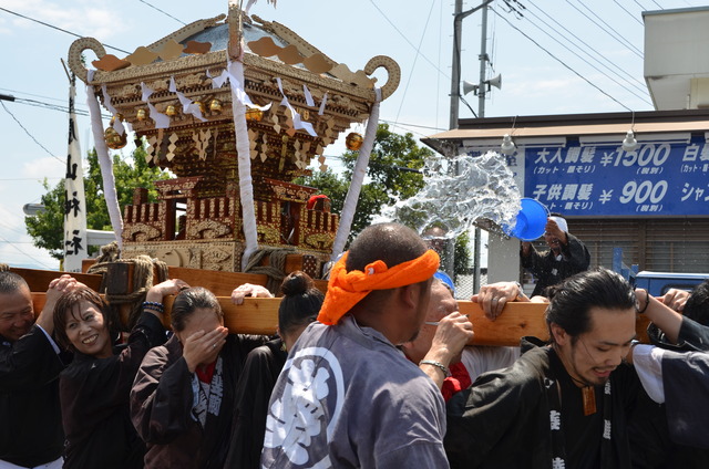 神輿を担ぐ人々が水をかけられている写真