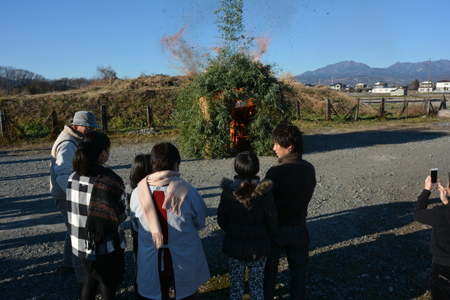 火のついた小屋を見ている人々の写真