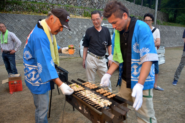 焼き鳥を焼く法被を着た男性達の写真