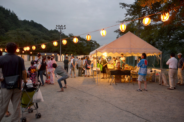 提灯が灯り、屋台がたくさん出ている祭りの様子の写真