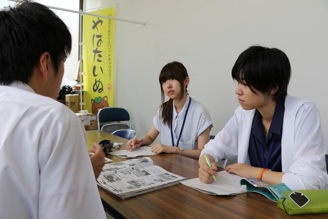 (写真)制作会議を行う職員と2人の大学生