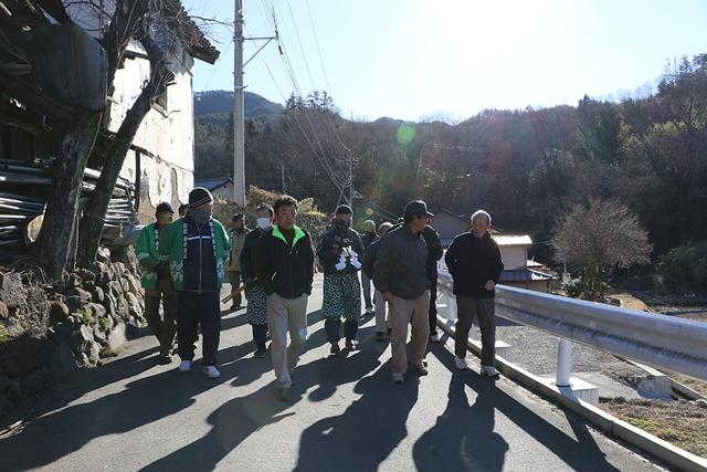 町の中を緑の法被を着ている男性がで歩いている写真