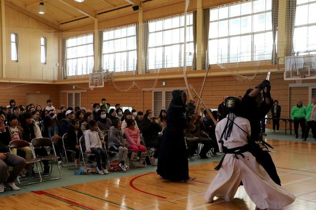 体育館で剣道をしているのを見ている多くの人々の写真